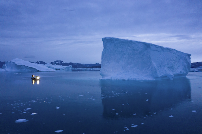 Una embarcación navega por la noche muy cerca de glaciares enormes, en el este de Groenlandia, el 15 de agosto de 2019.