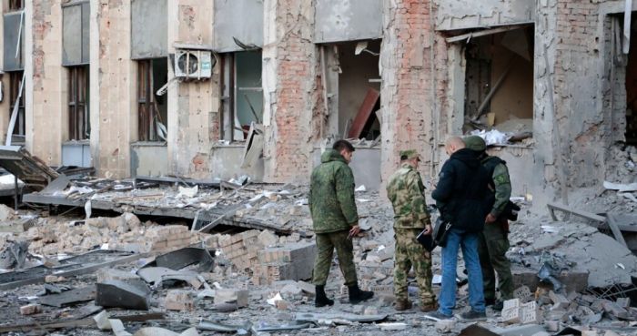 Investigadores revisan un lugar tras un ataque cerca de un edificio administrativo en Donetsk, la capital de la autoproclamada República Popular de Donetsk, en el este de Ucrania, el domingo 16 de octubre de 2022. Según la misión de la República Popular de Donetsk en el Centro Conjunto de Control y Coordinación, se lanzaron seis proyectiles de calibre 155 milímetros a Donetsk en la madrugada del domingo.