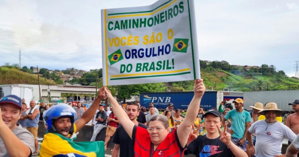 Una residente sostiene un cartel que dice en portugués: "Camioneros, ustedes son el orgullo de Brasil" para mostrar su apoyo a los conductores de carga que estacionaron sus camiones de carga en la carretera entre Río de Janeiro y Sao Paulo para protestar por la derrota electoral el día anterior del Presidente Jair Bolsonaro, el lunes 31 de octubre de 2022, en Barra Mansa, estado de Río de Janeiro, Brasil.