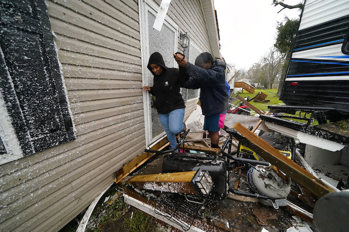 Personas recorren los escombros tras el paso de un tornado en Killona, Luisiana, a unos 48 kilómetros (30 millas) al oeste de Nueva Orleans, en el distrito St. James, el miércoles 14 de diciembre de 2022.