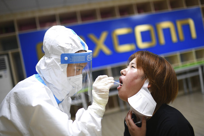 Una trabajadora médica toma muestras para una prueba de COVID-19 de una persona que trabaja en la fábrica de Foxconn en Wuhan, en el centro de la provincia china de Hubei, el jueves 5 de octubre de 2022.