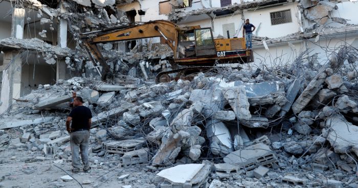 En esta fotografía del martes 15 de junio de 2021, trabajadores retiran los escombros de un edificio destruido por un bombardeo israelí, en Ciudad de Gaza.