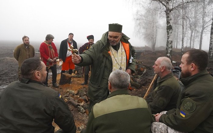 Un capellán bendice a soldados de la Guardia Nacional ucraniana con motivo de la Navidad en su posición cerca de la frontera rusa, cerca de Járkiv, Ucrania, el sábado 24 de diciembre de 2022.