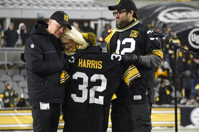 Art Rooney II, izquierda, presidente de los Steelers de Pittsburgh, la viuda de Franco Harris, Dana, centro, y su hijo Dok, asistieron a la ceremonia del retiro del jersey con el número 32 de Harris al medio tiempo del juego de la NFL en contra de los Raiders de Las Vegas, el sábado 24 de diciembre de 2022.