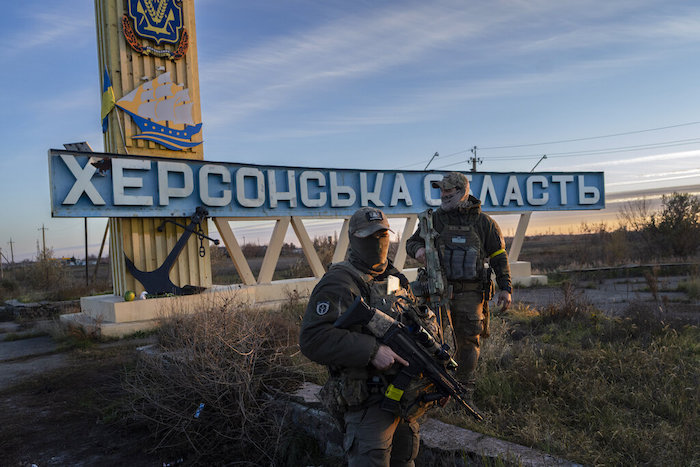 Dos soldados ucranianos están parados frente a un cartel que dice "Región de Jersón" en las afueras de Jersón, sur de Ucrania, 14 de noviembre de 2022.