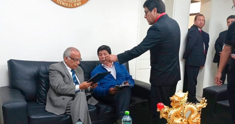 En esta foto proporcionada por la Oficina de Administración de la policía de Perú, el expresidente Pedro Castillo, segundo desde la izquierda, y el exprimer Ministro Aníbal Torres, en el extremo izquierdo, se sientan mientras el Fiscal Marco Huaman se encuentra en el centro dentro de una estación de policía en Lima, Perú, el miércoles 7 de diciembre de 2022.