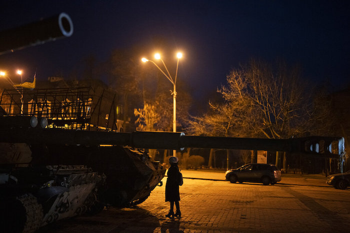 Una mujer parada frente a vehículos blindados y tanques rusos destruidos en el centro de Kiev, Ucrania, el viernes 20 de enero de 2023.