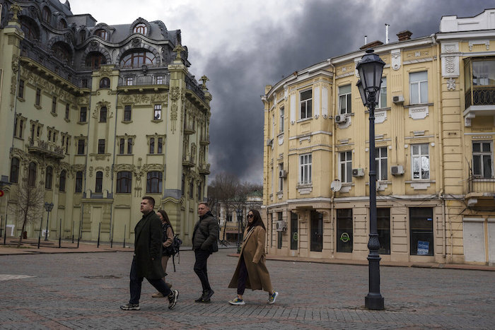Personas caminan por una calle cerca de humo por un ataque en Odesa, Ucrania, el 3 de abril de 2022. 
