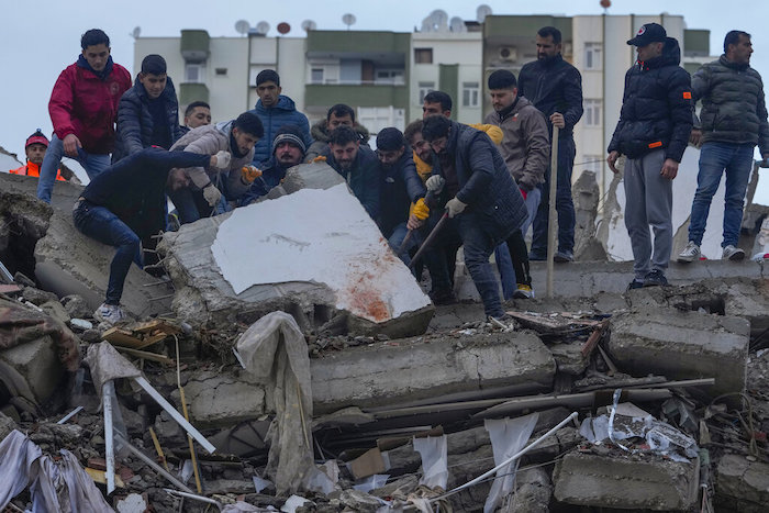 Un grupo de personas busca entre los escombros de un edificio a sobrevivientes tras un sismo, en Adana, Turquía, el lunes 6 de febrero de 2023.