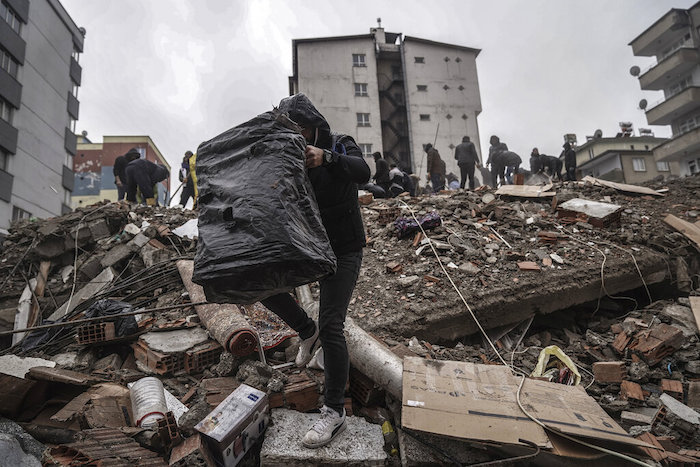 Varias personas y efectivos de los equipos de rescate buscan sobrevivientes entre los escombros de un edificio derrumbado por un temblor en Gaziantep, Turquía, el 6 de febrero de 2023.