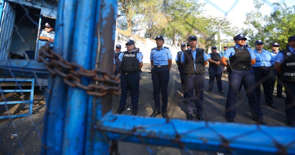 Policías montan guardia en un centro de detención conocido como "El Chipote", asociado a la tortura durante la dictadura de Somoza (1937-1979) y oficialmente llamado Dirección de Auxilio Judicial, mientras se enfrentan a manifestantes, del otro lado del cerco, que protestan los arrestos de manifestantes antigubernamentales en Managua, Nicaragua, 25 de abril de 2018.