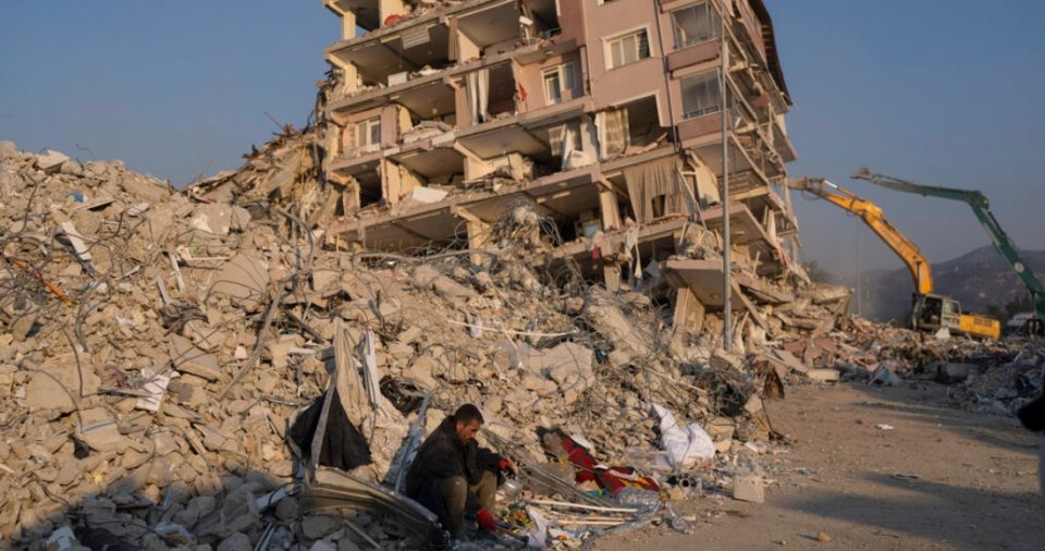 Un hombre se sienta en los escombros de un edificio derrumbado por los sismos recientes, el domingo 12 de febrero de 2023, en Antioquía, Turquía.