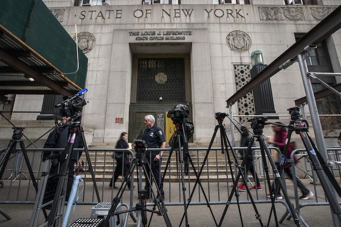 Gente pasa frente al tribunal y cámaras y equipos instalados por la prensa a la espera de la resolución del gran jurado sobre Donald Trump, jueves 23 de marzo de 2023. 