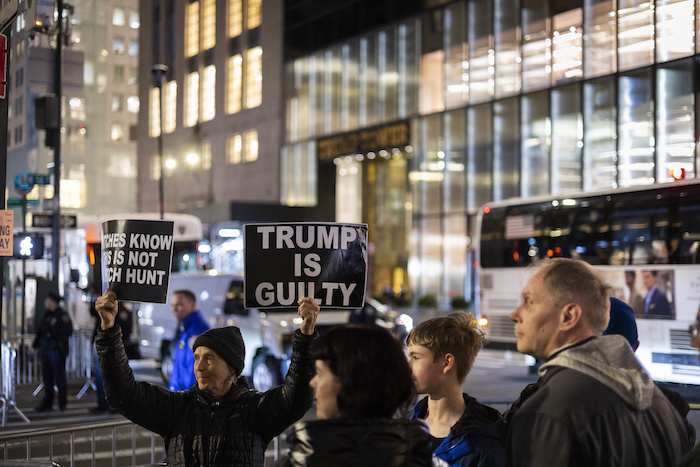 Un manifestante sostiene pancartas contra el expresidente Donald Trump frente a la Torre Trump en Nueva York la noche del lunes 3 de abril de 2023.