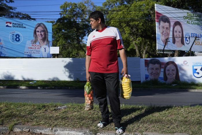 Virgilio Benítez, un camionero de 39 años, vende frutas y verduras en la esquina de una calle rodeada de carteles electorales, en Asunción, Paraguay, el viernes 21 de abril de 2023.