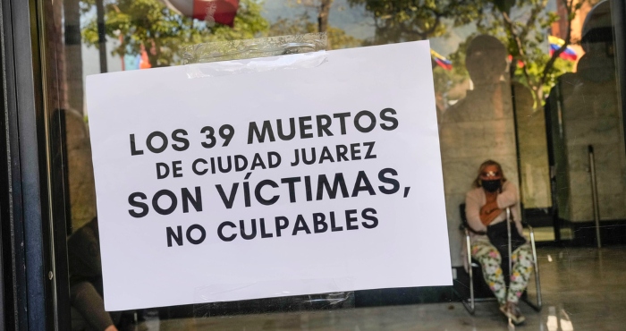 Un cartel que defiende que los migrantes son víctimas y no culpables está pegado en una puerta de cristal de la embajada de México en Caracas, Venezuela, el miércoles 29 de marzo de 2023. 