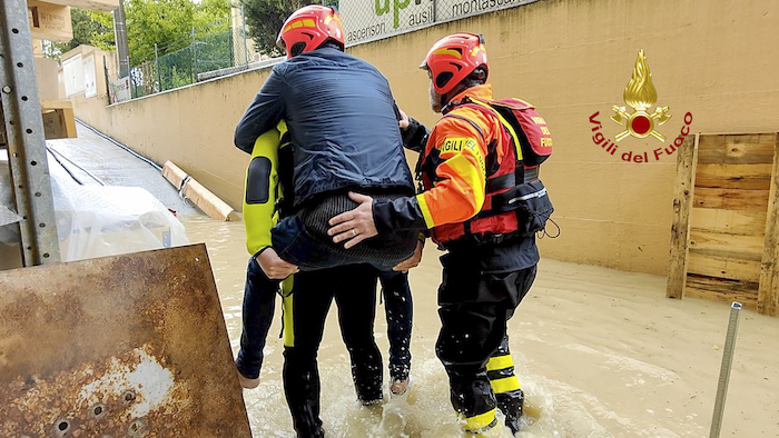 Esta foto facilitada por los bomberos italianos muestra a socorristas que retiran a una persona de una casa inundada en Riccione, en la región norteña italiana de Emilia-Romaña, el martes 16 de mayo de 2023.