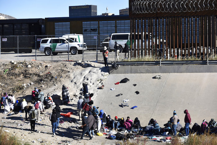 En esta imagen de archivo, migrantes esperan para cruzar la frontera entre Estados Unidos y México desde Ciudad Juárez, México, cerca de autos de la patrulla fronteriza estadounidense en El Paso, Texas, el 14 de diciembre de 2022.