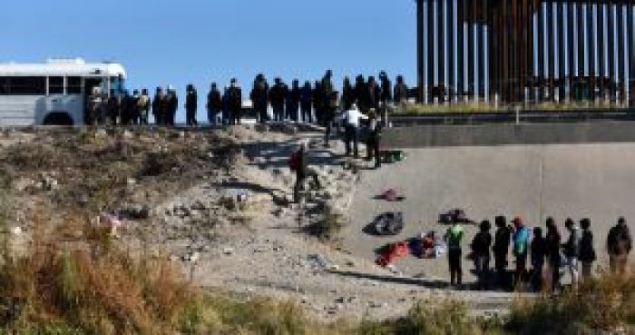 Decenas de migrantes esperan a subir a un autobús del Gobierno estadounidense tras cruzar la frontera desde Ciudad Juárez, México, a El Paso, Texas, el 12 de diciembre de 2022.